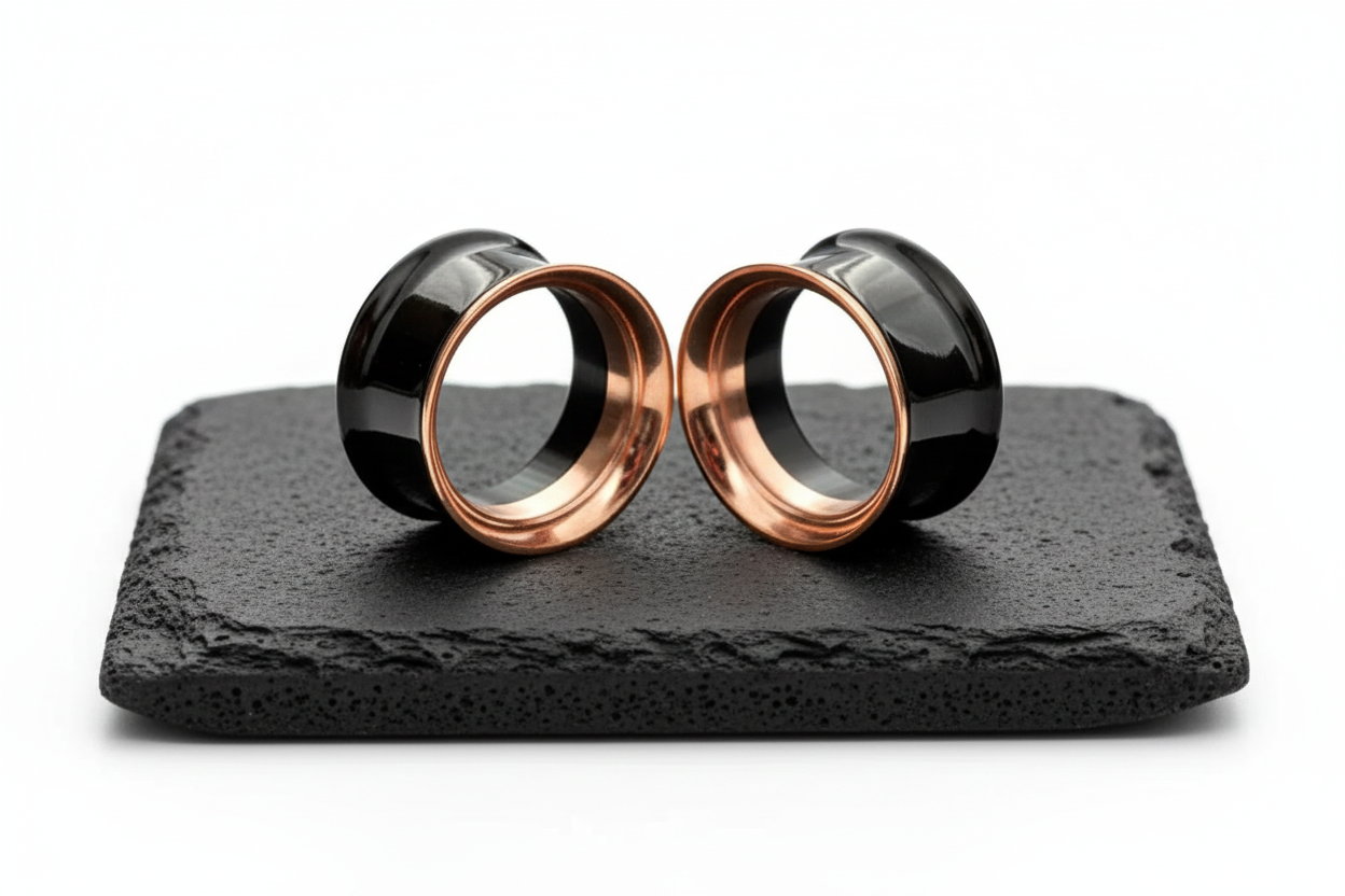 Black and Rose Gold Steel Tunnels (6mm-19mm) photographed on rock in a clean white studio.