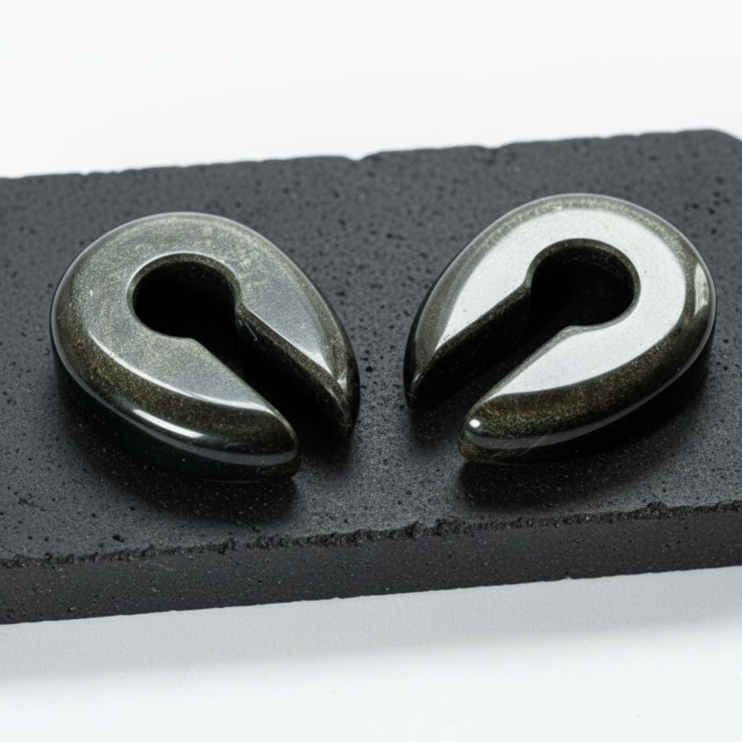 Golden Obsidian Stone Hangers (6-10mm) on a dark stone against a white studio background.