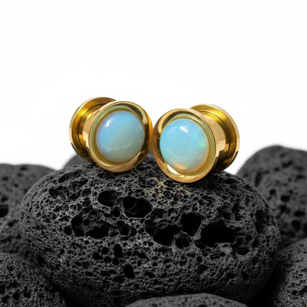 Golden stainless steel plugs with a milky white and iridescent Opalite stone inlay. Gauges for stretched ear lobes.