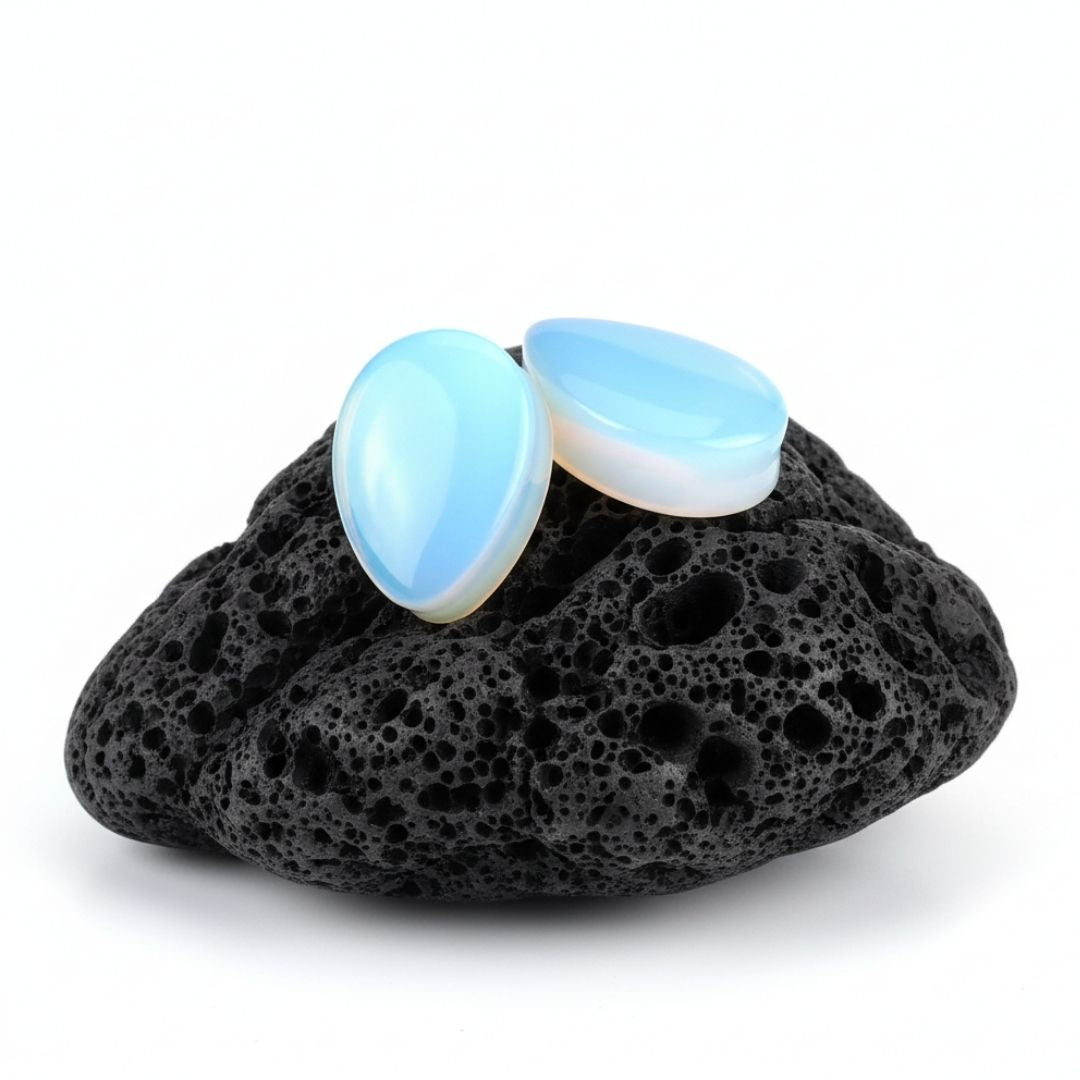 A pair of double flared Opalite teardrop plugs (gauges) displayed against a dark background for stretched ear jewelry alt fashion.