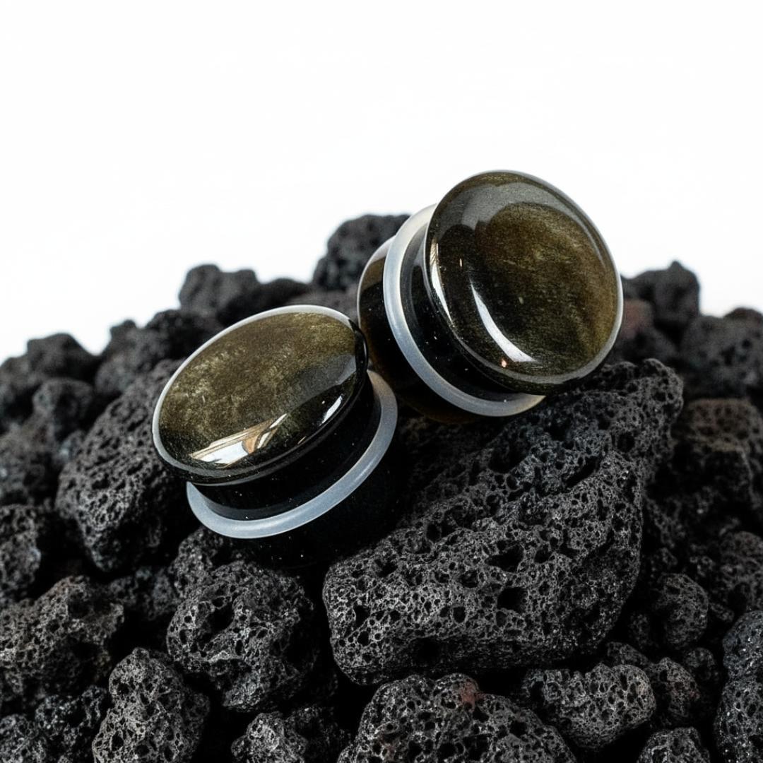 Single flare golden obsidian stone plugs shown up close. Dark gauges with gold flashes, suitable for stretched ear piercings