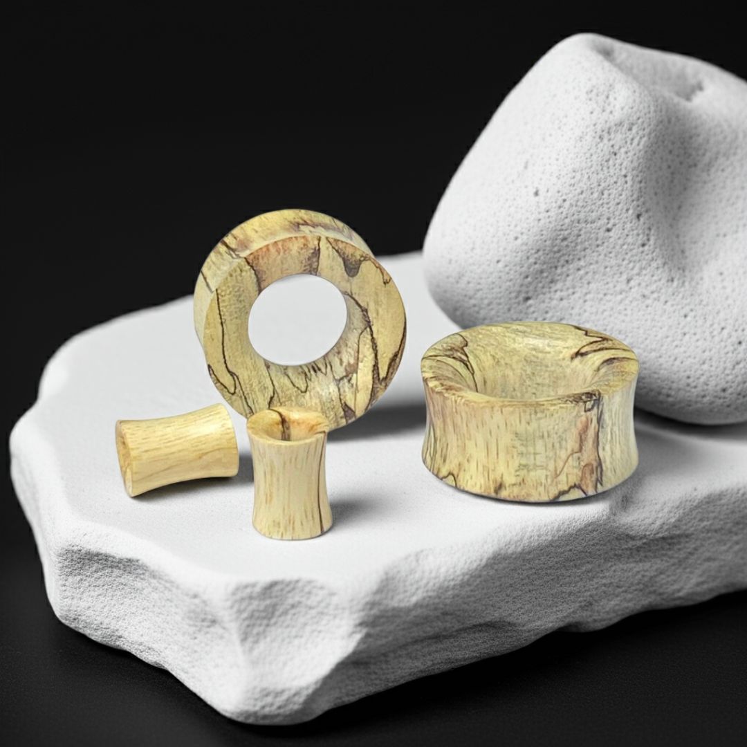 Wooden ear gauges on a white stone surface with a black background