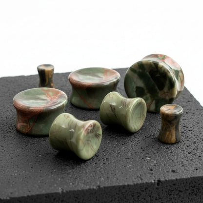 Close-up of Amber Agate Stone plugs (6mm-25mm) on a rock against a clean white background.