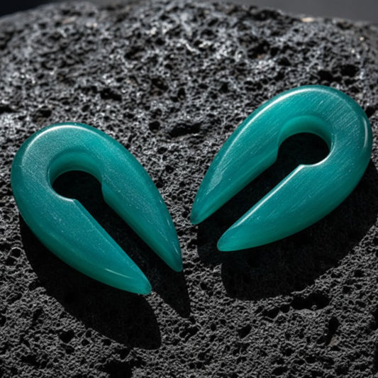 Aqua Dragon Eye Stone Hangers (6mm-10mm) on dark volcanic rock with dramatic lighting.