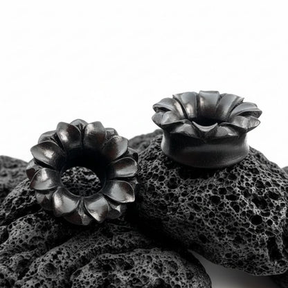 Pair of dark Areng wood tunnels with a detailed carved lotus design, shown as organic gauges for stretched lobes.
