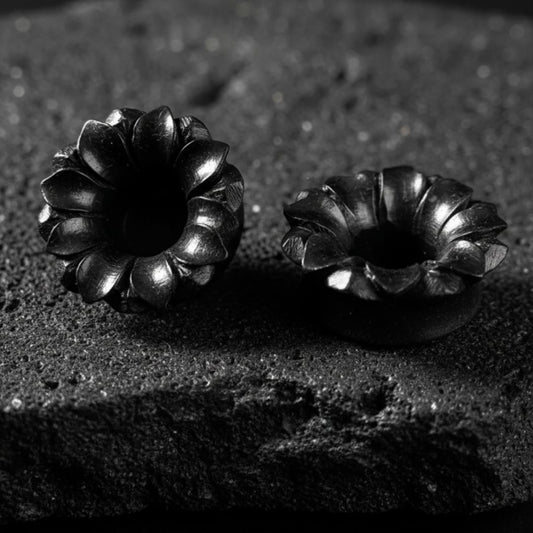 Pair of dark Areng wood tunnels with a detailed carved lotus design, shown as organic gauges for stretched lobes.