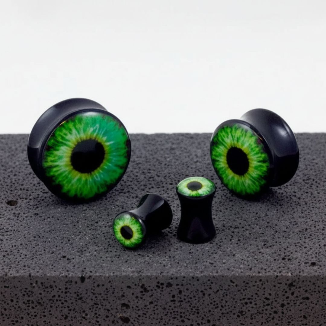 Basilisk Eye Acrylic Plugs in sizes 3mm-30mm shown on a rock against a white background.