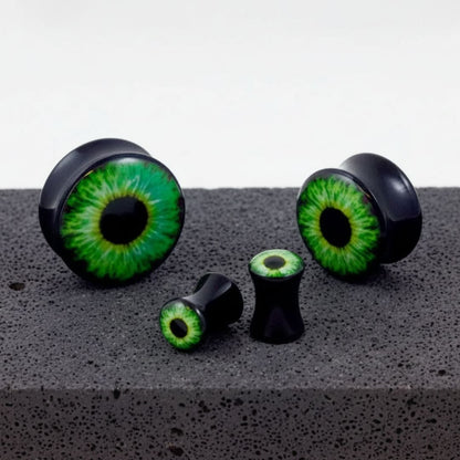Basilisk Eye Acrylic Plugs in sizes 3mm-30mm shown on a rock against a white background.