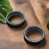 Gem Lined Black Steel Tunnels, with a hint of shine against a dark backdrop.