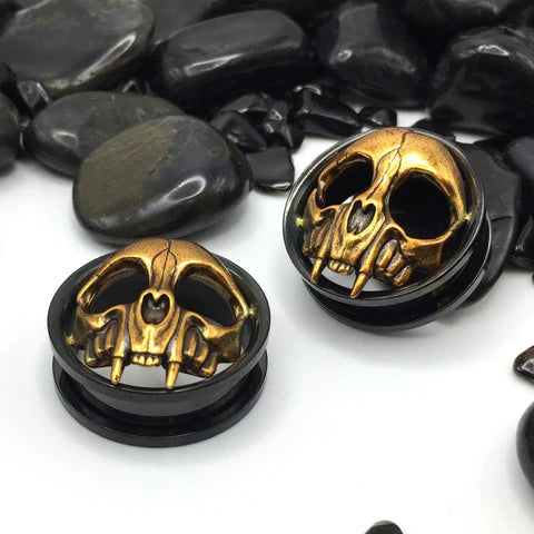 Golden Skull Steel Tunnels - black tunnel showcasing a 3D bronze skull with sharp fangs