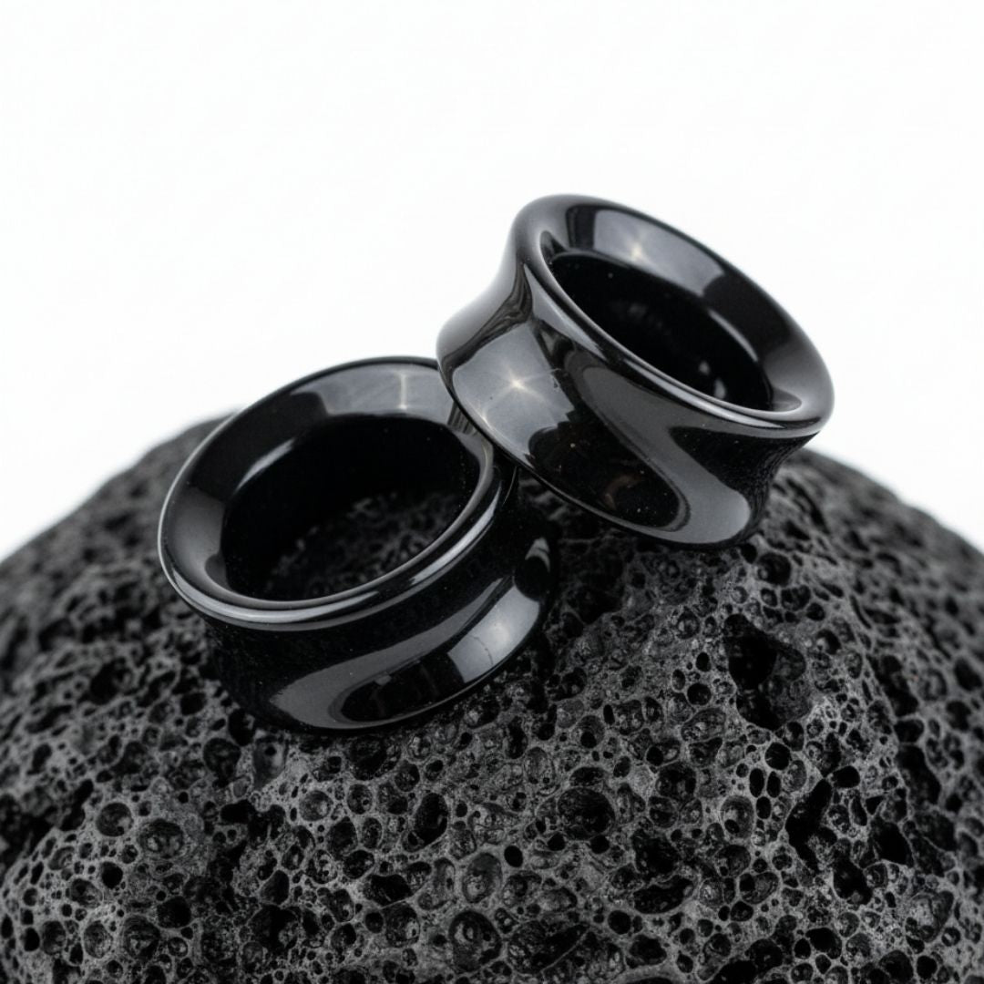 Pair of polished Black Agate stone tunnels/gauges on a dark background. Stretched ear jewelry sizes 6mm to 38mm.