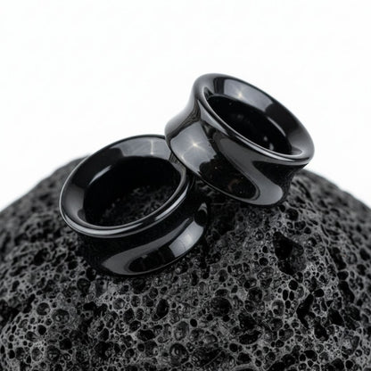 Pair of polished Black Agate stone tunnels/gauges on a dark background. Stretched ear jewelry sizes 6mm to 38mm.