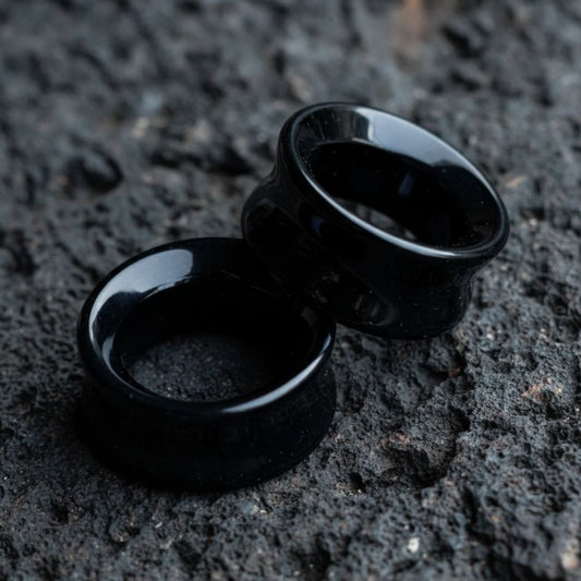 Pair of polished Black Agate stone tunnels/gauges on a dark background. Stretched ear jewelry sizes 6mm to 38mm.