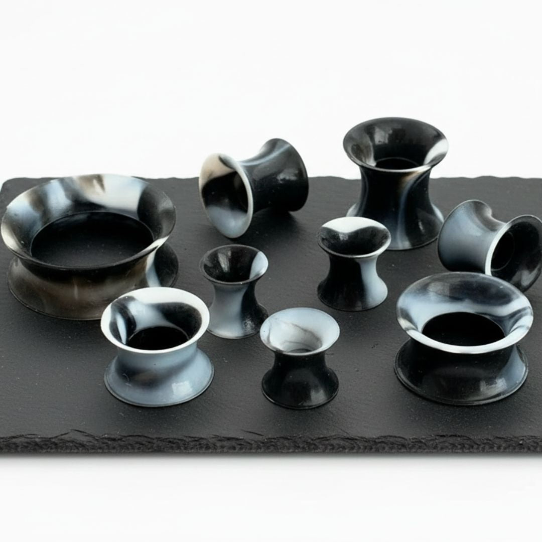 Black and White Silicone Skins (5mm-25mm) on volcanic rock, white studio background.