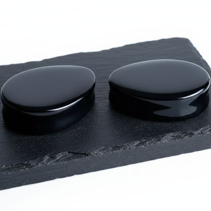 Studio photo of Onyx Stone Teardrop Plugs on rock against a clean white background.