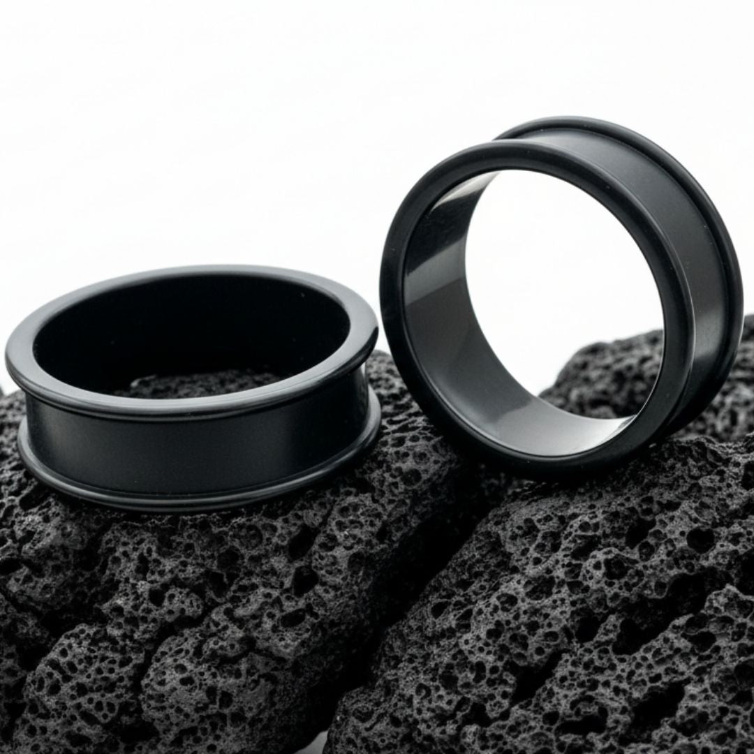 Pair of black thin-flare silicone tunnels (gauges) displayed against a dark background, showing the soft material texture.