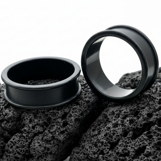 Pair of black thin-flare silicone tunnels (gauges) displayed against a dark background, showing the soft material texture.
