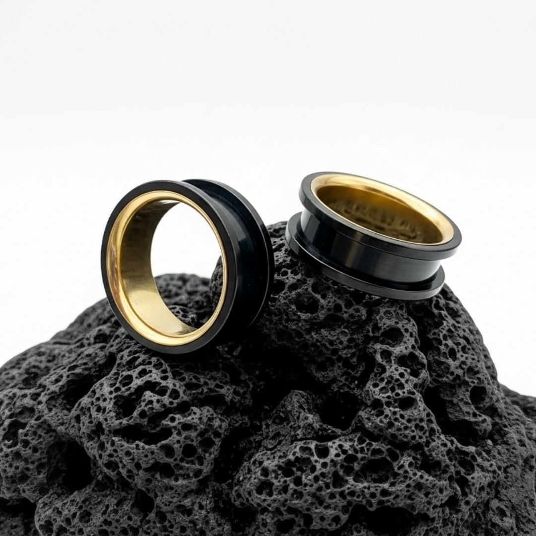 Black and Gold steel tunnels for stretched ears on black volcanic stone