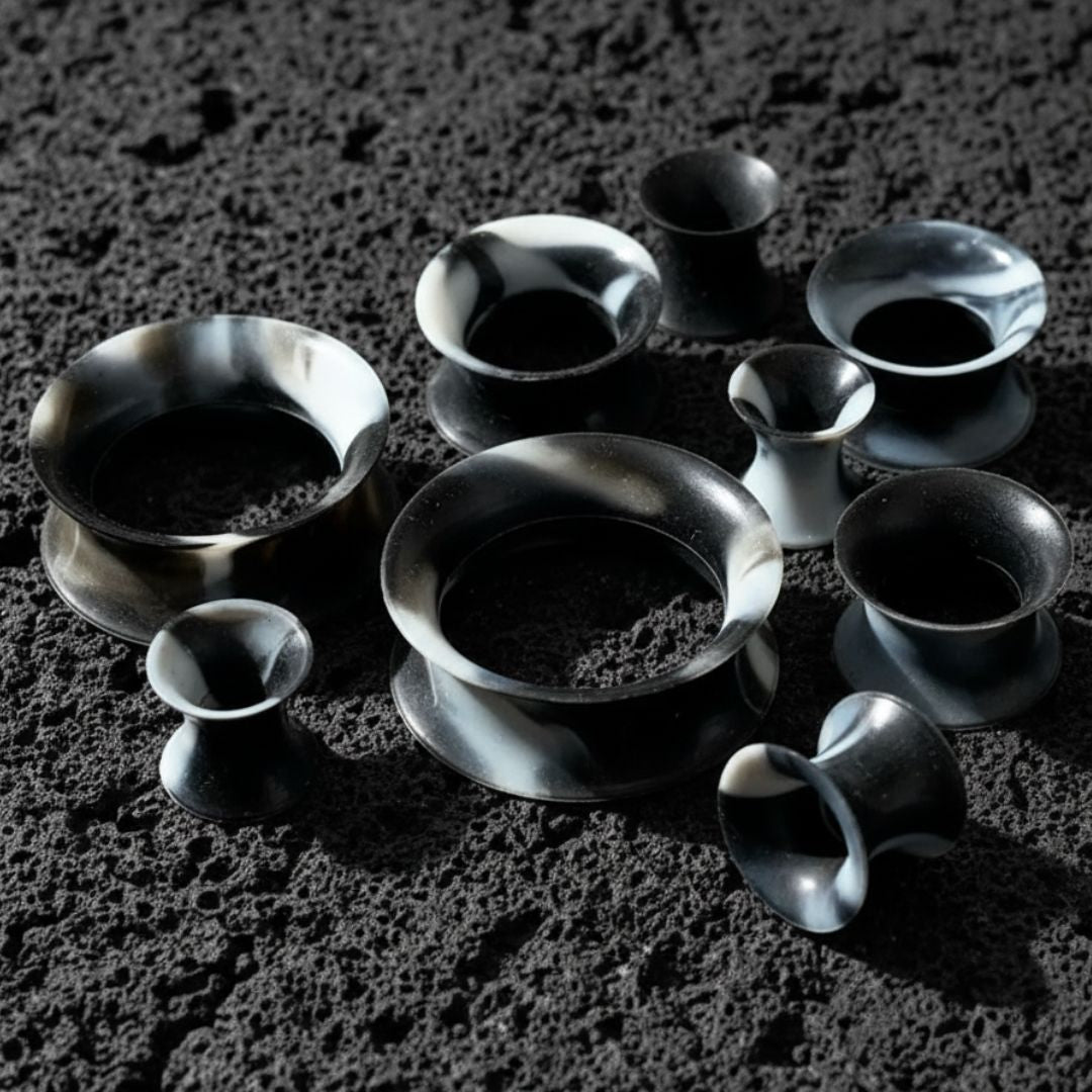 Black and White Silicone Skins from 5mm-25mm on dark volcanic rock with side light.