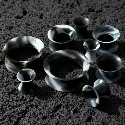 Black and White Silicone Skins from 5mm-25mm on dark volcanic rock with side light.