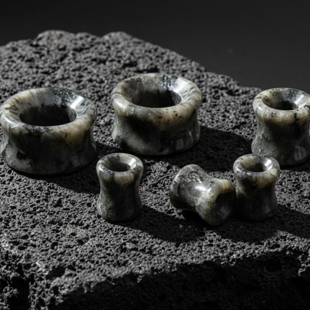 Black Labradorite Stone Tunnels (Larvikite) from 6mm to 30mm on volcanic rock.