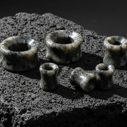Black Labradorite Stone Tunnels (Larvikite) from 6mm to 30mm on volcanic rock.