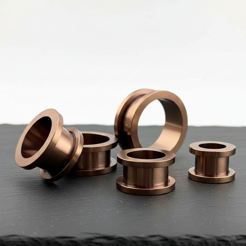 A pair of Bronze Plated 316L Steel tunnels shot on stone in a clean white studio.