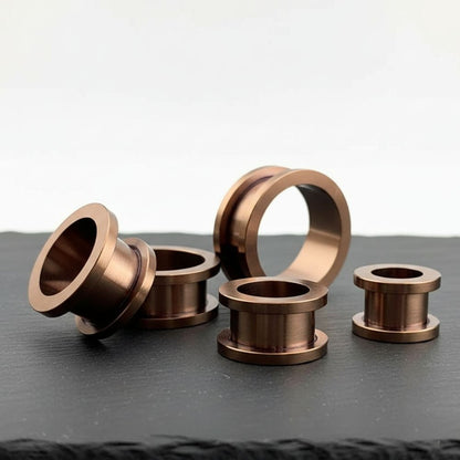 A pair of Bronze Plated 316L Steel tunnels shot on stone in a clean white studio.