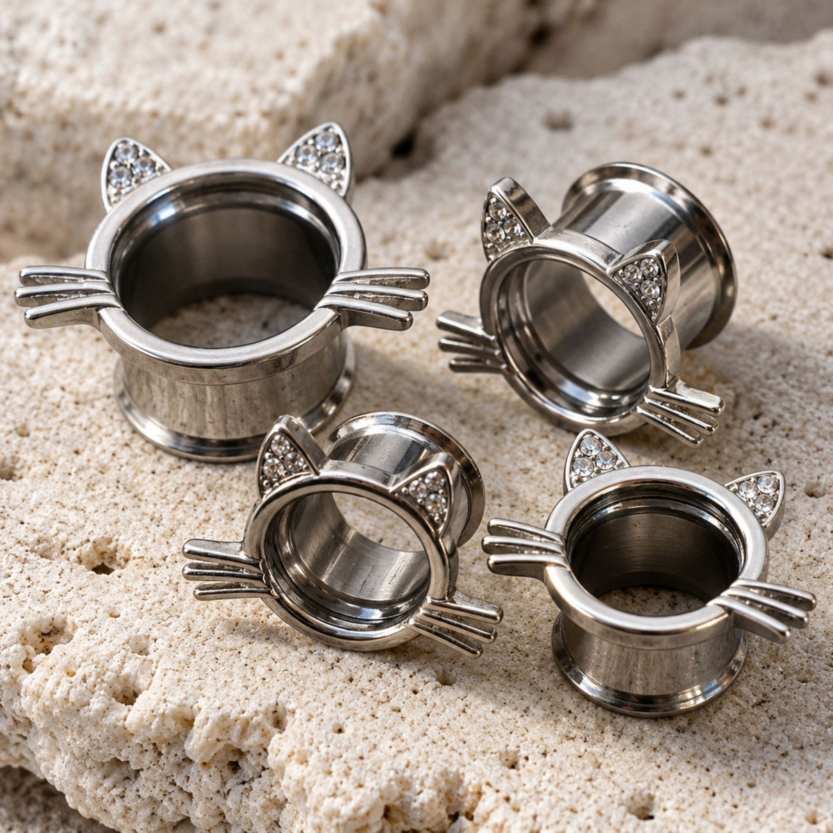 A pair of Kawaii Neko Steel Tunnels (6mm-16mm) sit on stone against a clean white background.