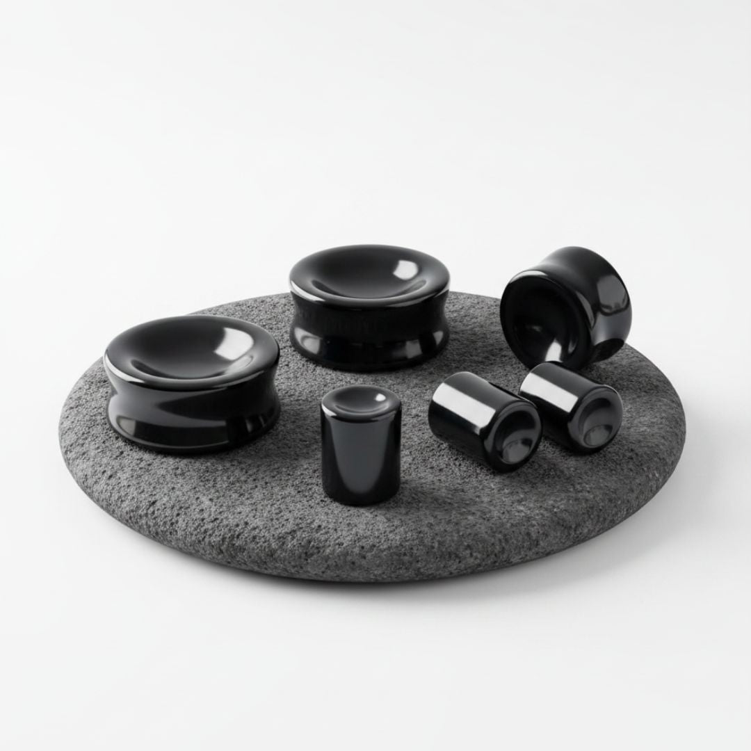A pair of Concave Onyx Stone Plugs shown on volcanic stone against a white background.