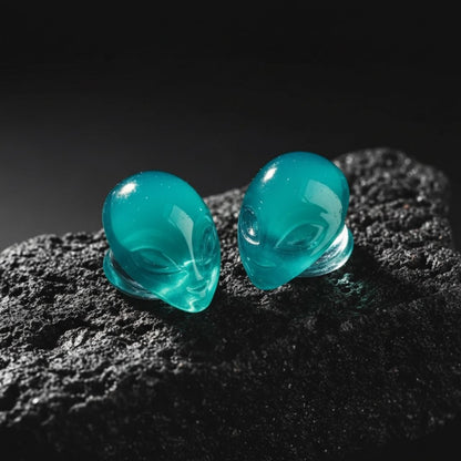 Pair of black and white glass plugs shaped like alien heads for stretched ears and body piercing jewelry.