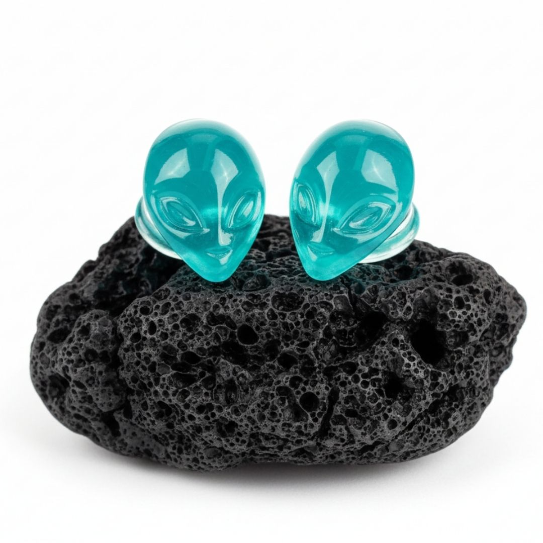 Pair of black and white glass plugs shaped like alien heads for stretched ears and body piercing jewelry.