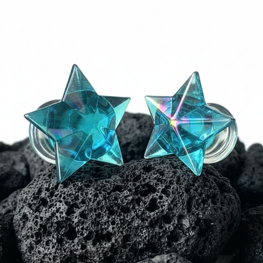 Pair of clear glass starfish plugs for stretched ears, shown on a dark background. Alt fashion body jewelry, sizes 6mm to 16mm.