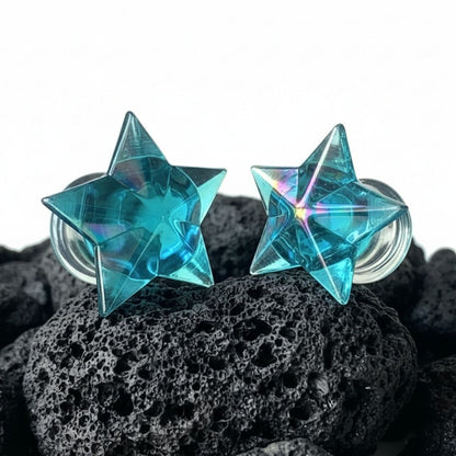 Pair of clear glass starfish plugs for stretched ears, shown on a dark background. Alt fashion body jewelry, sizes 6mm to 16mm.
