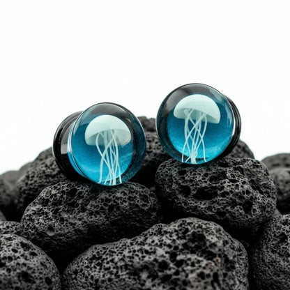 Pair of clear glass plugs with white jellyfish design inside, ideal for stretched ears, sold by ThePlugCrate.