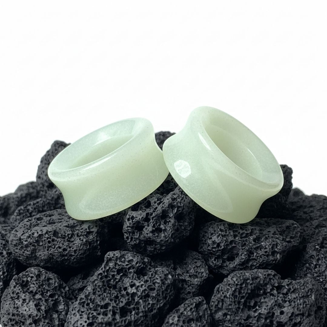 Pair of Glow In The Dark Moonstone Tunnels (gauges) on a dark background. Stretched ear jewelry sizes 6mm to 25mm.