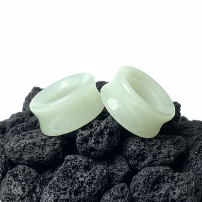 Pair of Glow In The Dark Moonstone Tunnels (gauges) on a dark background. Stretched ear jewelry sizes 6mm to 25mm.