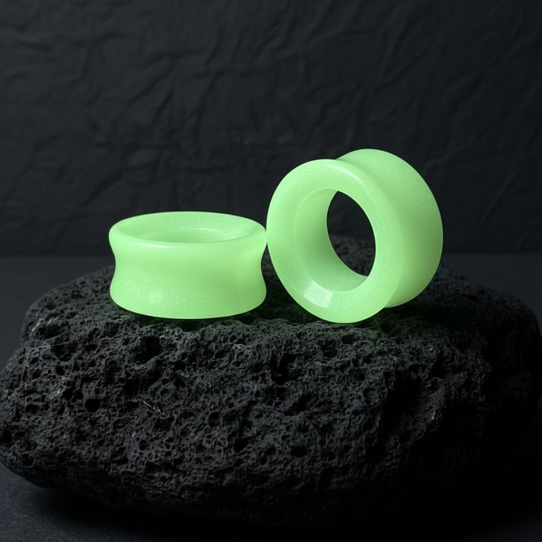 Pair of Glow In The Dark Moonstone Tunnels (gauges) on a dark background. Stretched ear jewelry sizes 6mm to 25mm.
