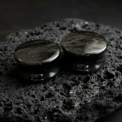 Pair of Golden Obsidian stone plugs (6mm to 25mm) showing the natural gold flash on the black stretched ear gauges.