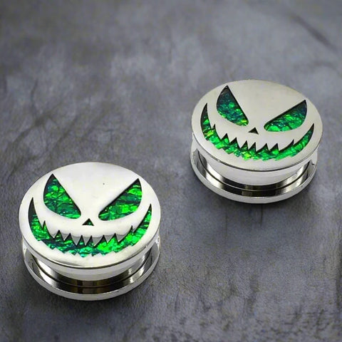 Steel plugs featuring a menacing jack-o'-lantern face on a shimmering green opal background.