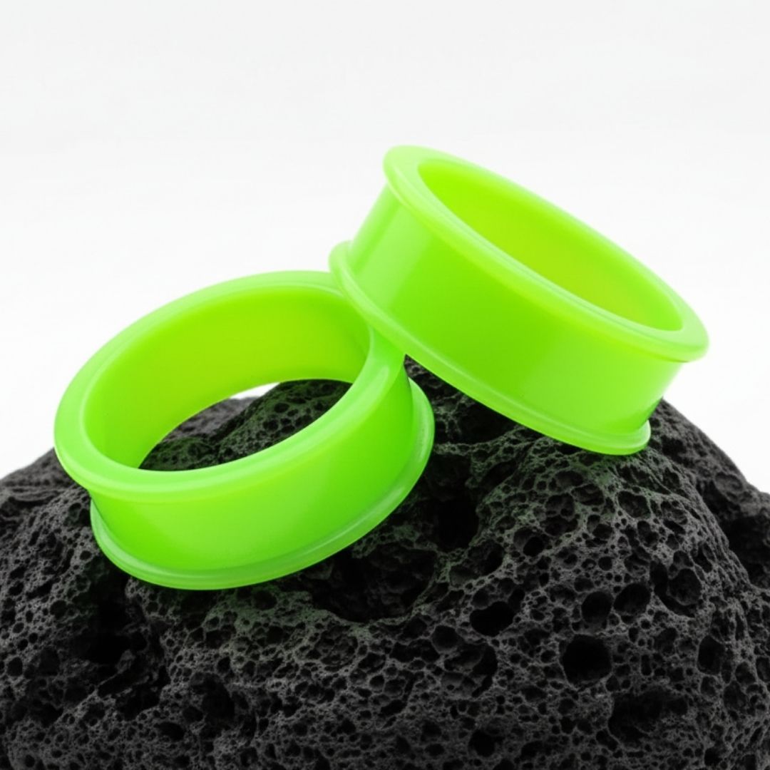 Close-up shot of neon green silicone tunnels (flexible eyelets) ranging in size, used for body modification.