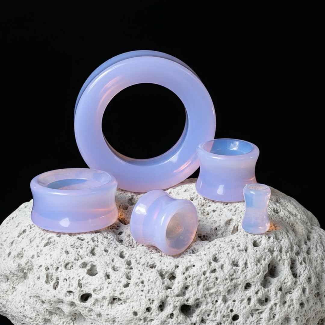 Set of glass ear gauges on a textured surface with a black background