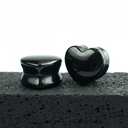 Onyx Stone Heart Plugs in various sizes (6mm-16mm) on a rock against a clean white background.