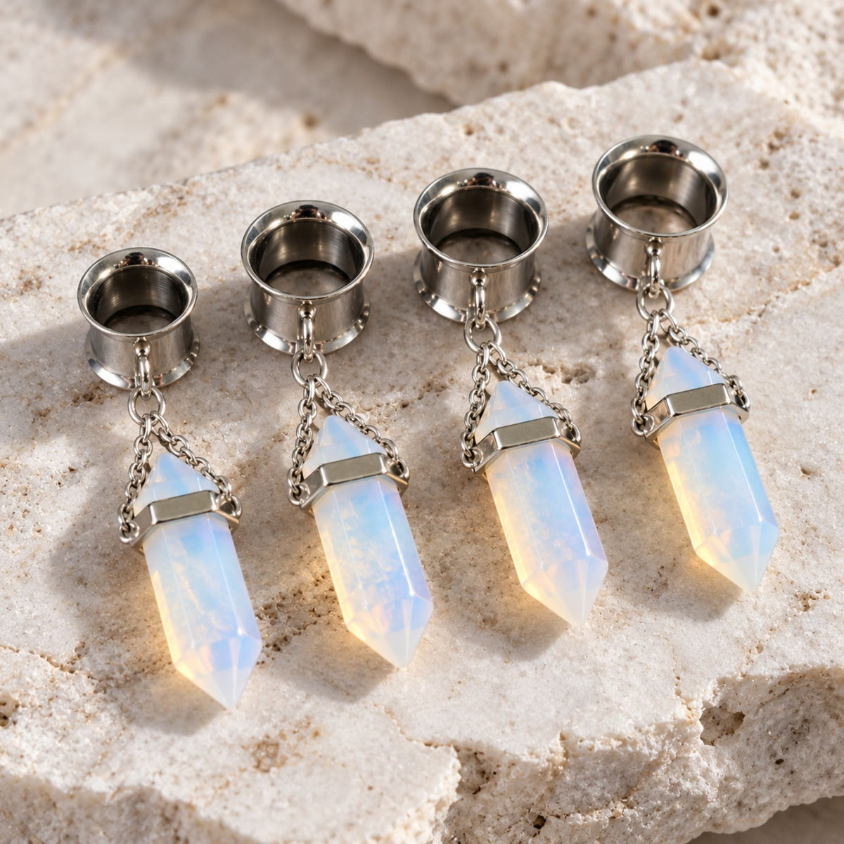 A pair of Steel Opalite Dangle Tunnels on a stone against a clean white background.