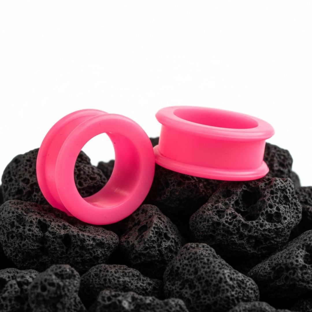A pair of hot pink silicone tunnels/gauges shown close up, designed for comfortable wear in stretched ear piercings.
