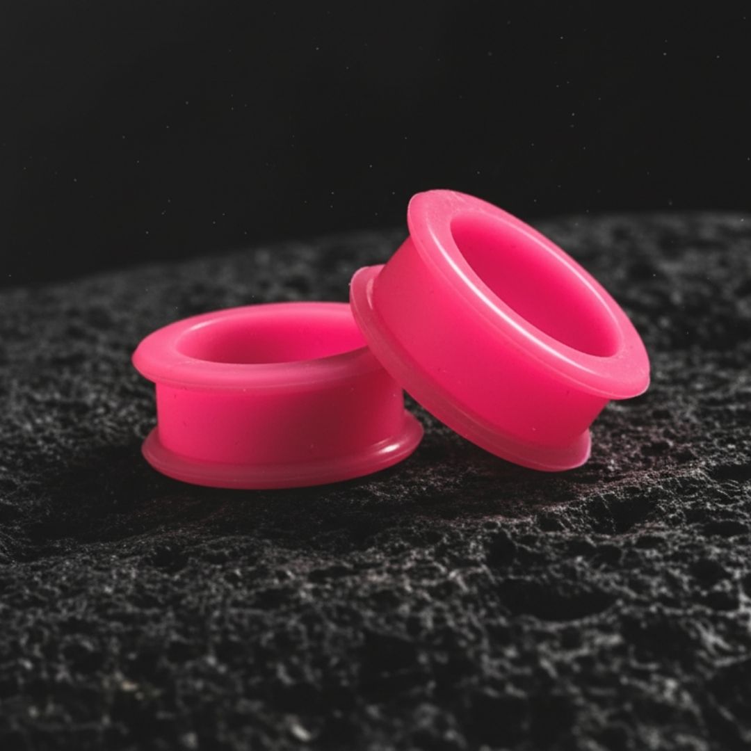 A pair of hot pink silicone tunnels/gauges shown close up, designed for comfortable wear in stretched ear piercings.