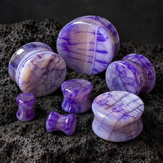 Purple Dragon Scale Agate Stone Plugs (6mm-25mm) on dark volcanic rock with dramatic lighting.