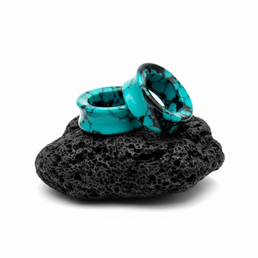 Close-up shot of Retro Turquoise stone tunnels (flared gauges) on a flat black surface, featuring unique earth tones.