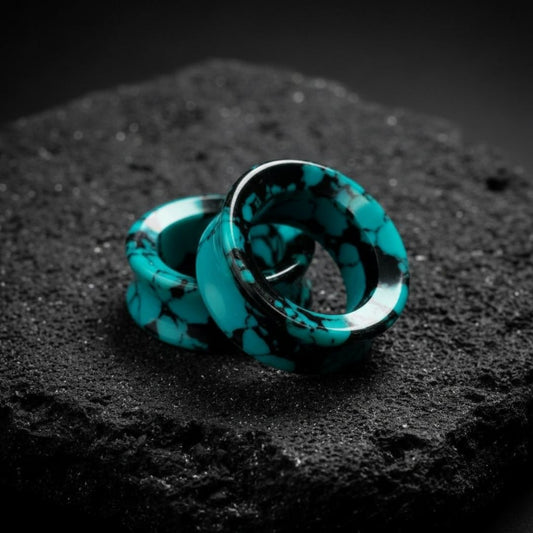 Close-up shot of Retro Turquoise stone tunnels (flared gauges) on a flat black surface, featuring unique earth tones.