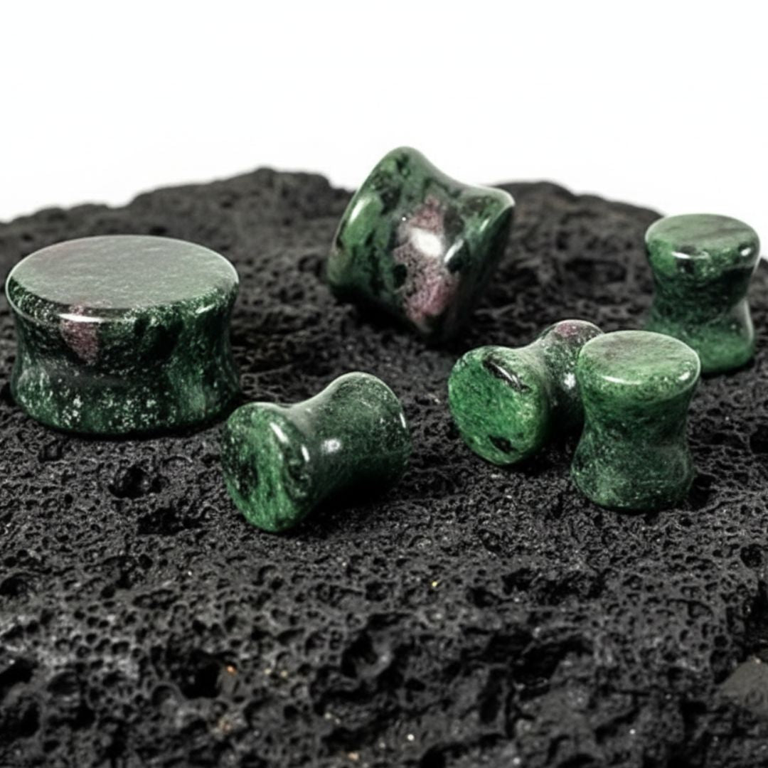 A pair of Ruby Zoisite Stone Plugs (6mm-25mm) on a rock against a white studio background.